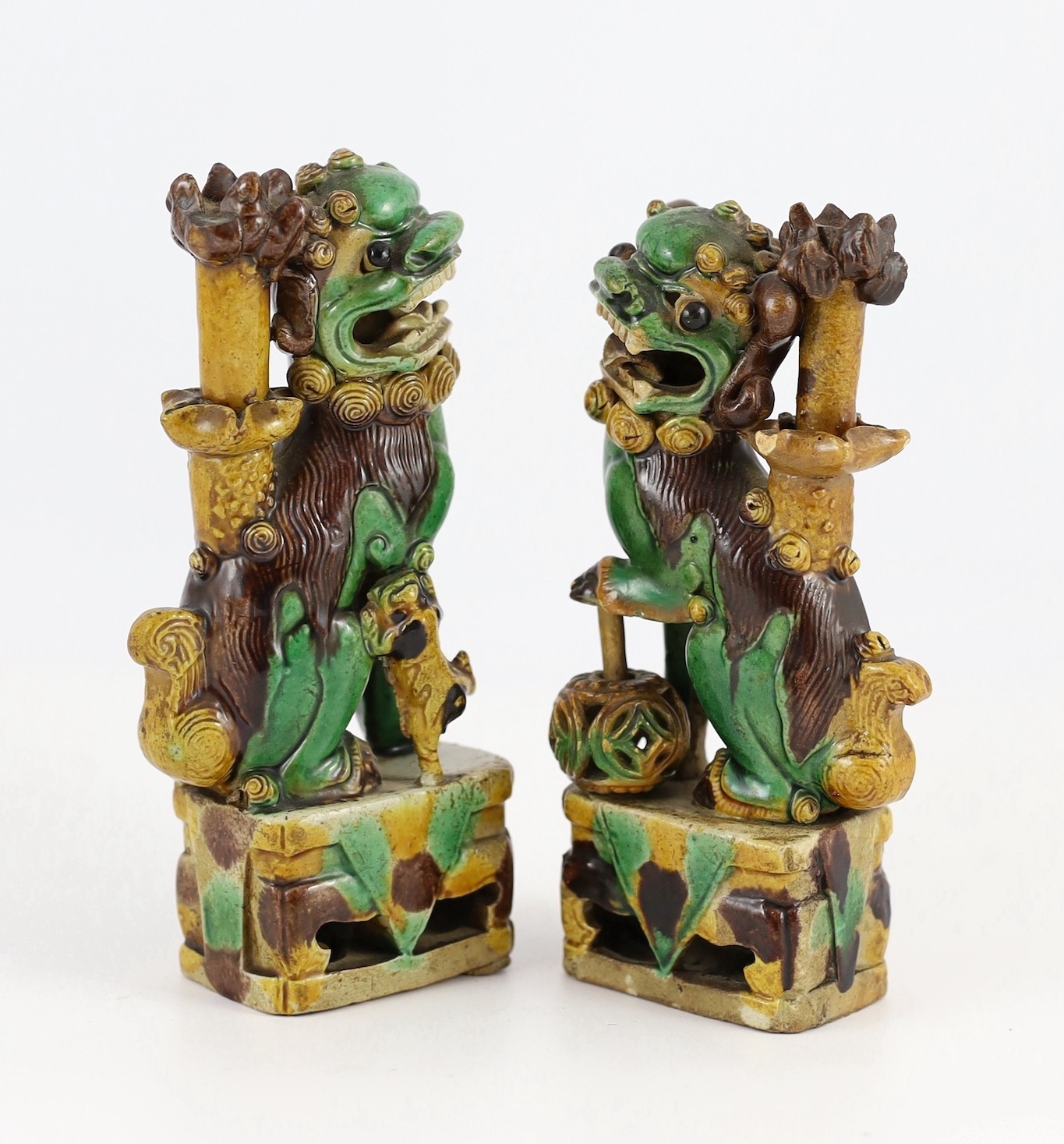 A pair of Chinese sancai-glazed biscuit Buddhist lion joss stick holders, Kangxi period, 15.5 and 16cm high, some restoration